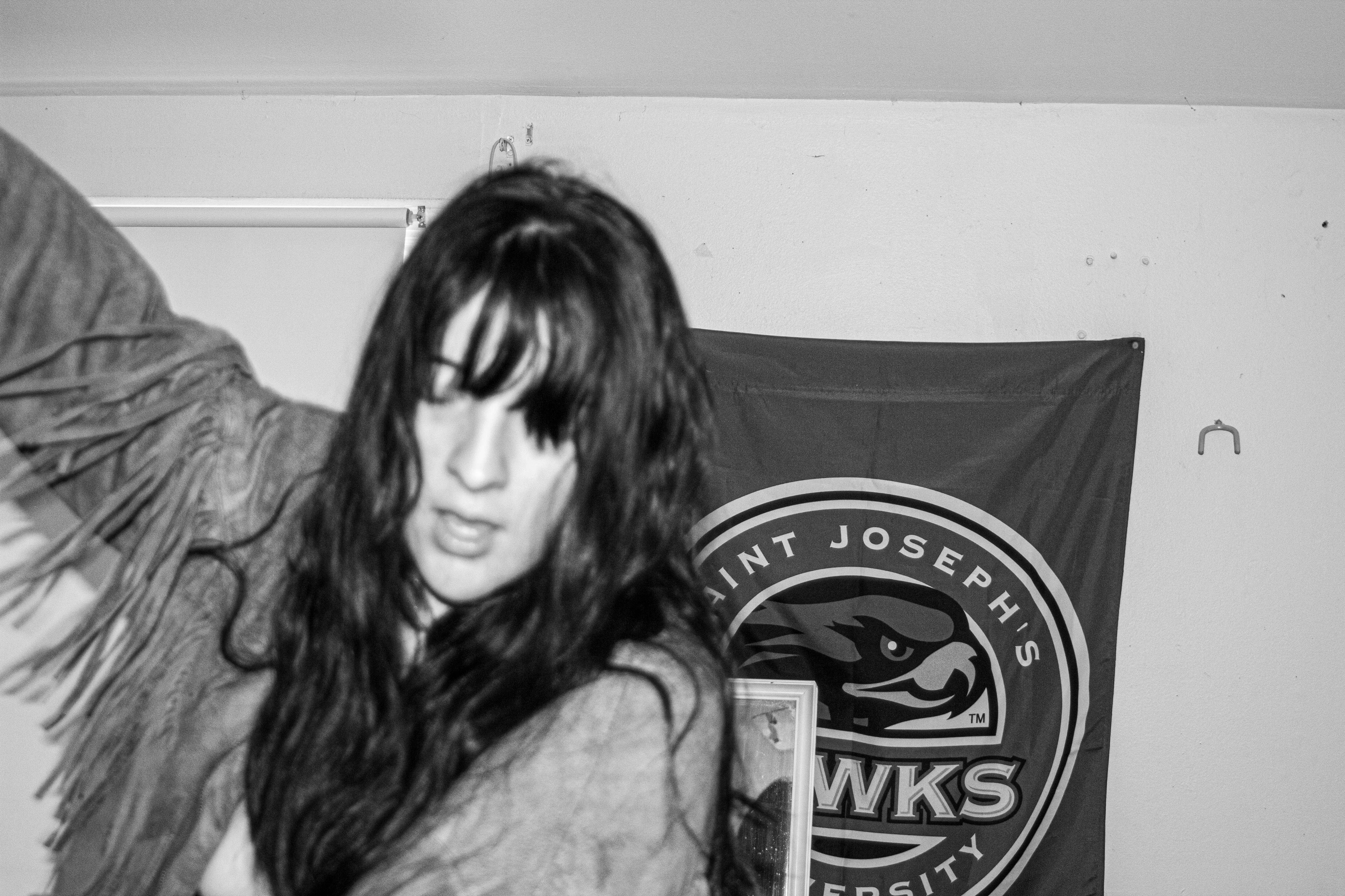 A woman wearing a cowboy tassel jacket is dancing. The image is in black and white and she has long dark hair.