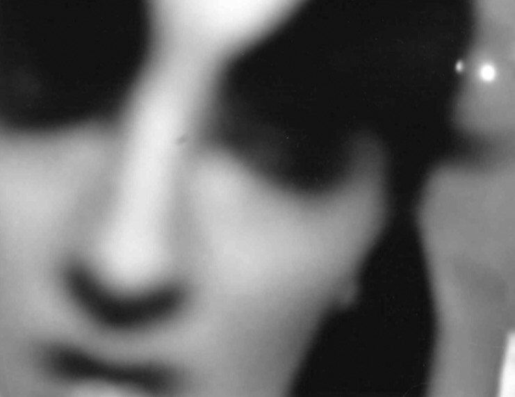A blurry zoomed in picture of a woman's face. The scene is in black and white and is blurry.