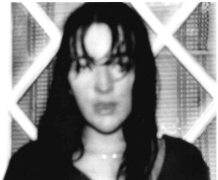 A woman's head in the rain. Her mouth is open, the image is in stark contrast and black and white and she is wearing a silver chain around her neck.